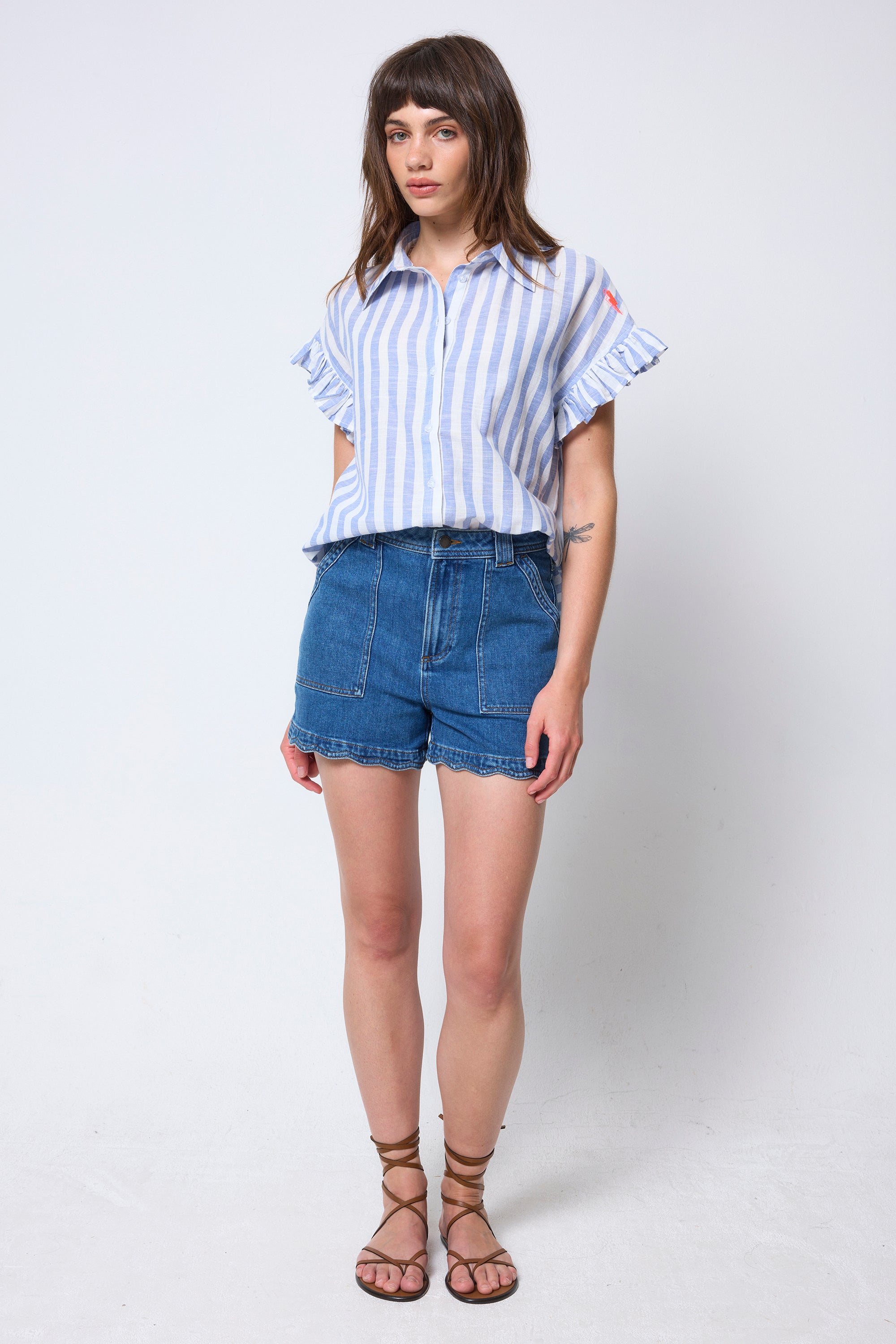Scamp & Dude Blue and White Stripe Frill Sleeve Shirt | Model wearing a striped shirt and denim shorts on a white background.