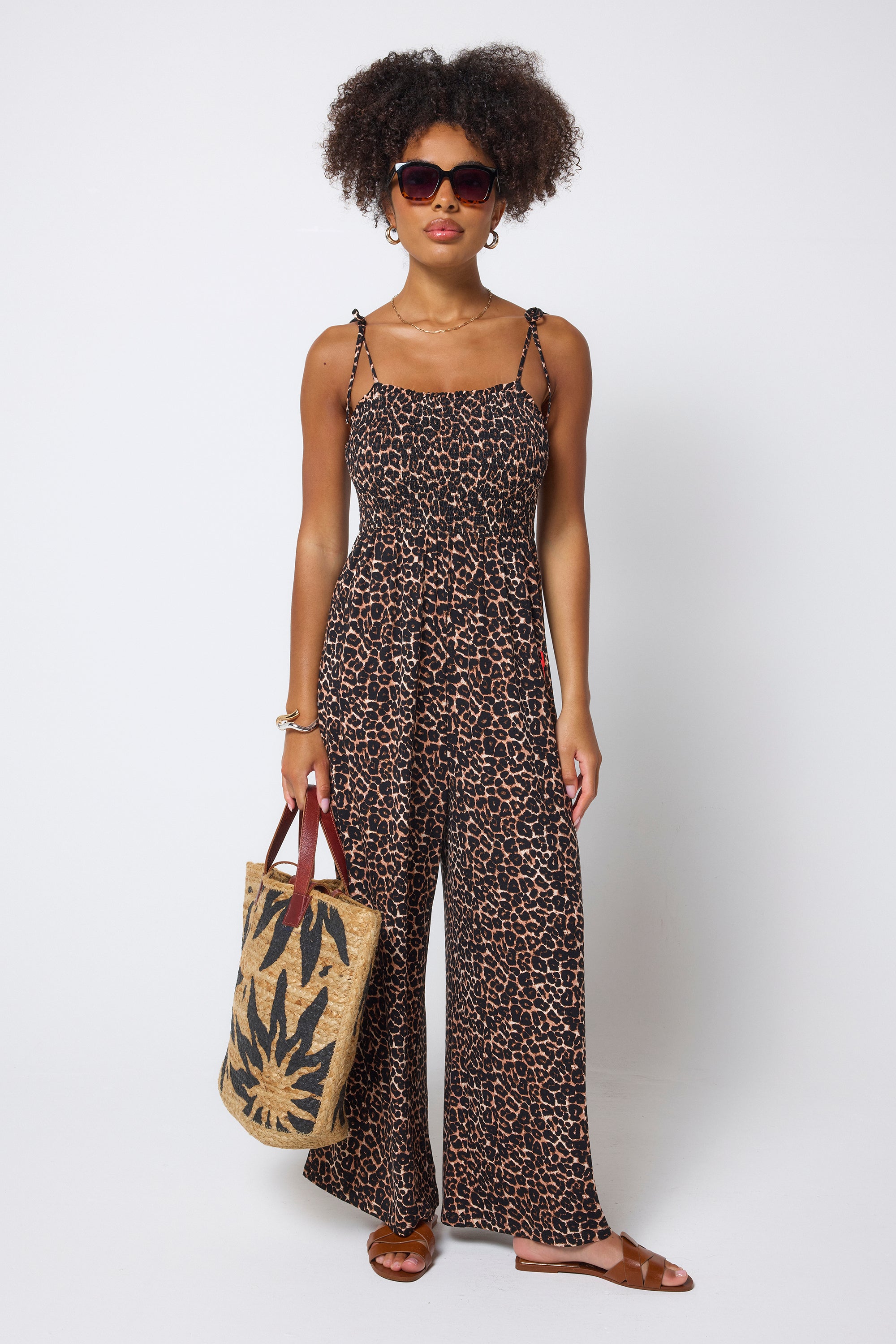 Scamp & Dude Neutral Jaguar Jersey Wide Leg Jumpsuit | Model wearing a neutral jaguar print jumpsuit holding a straw bag.