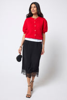 Scamp & Dude Black Lace Trim Midi Slip Skirt | Model wearing a black lace trim midi skirt with a white vest and red short sleeve cardigan.