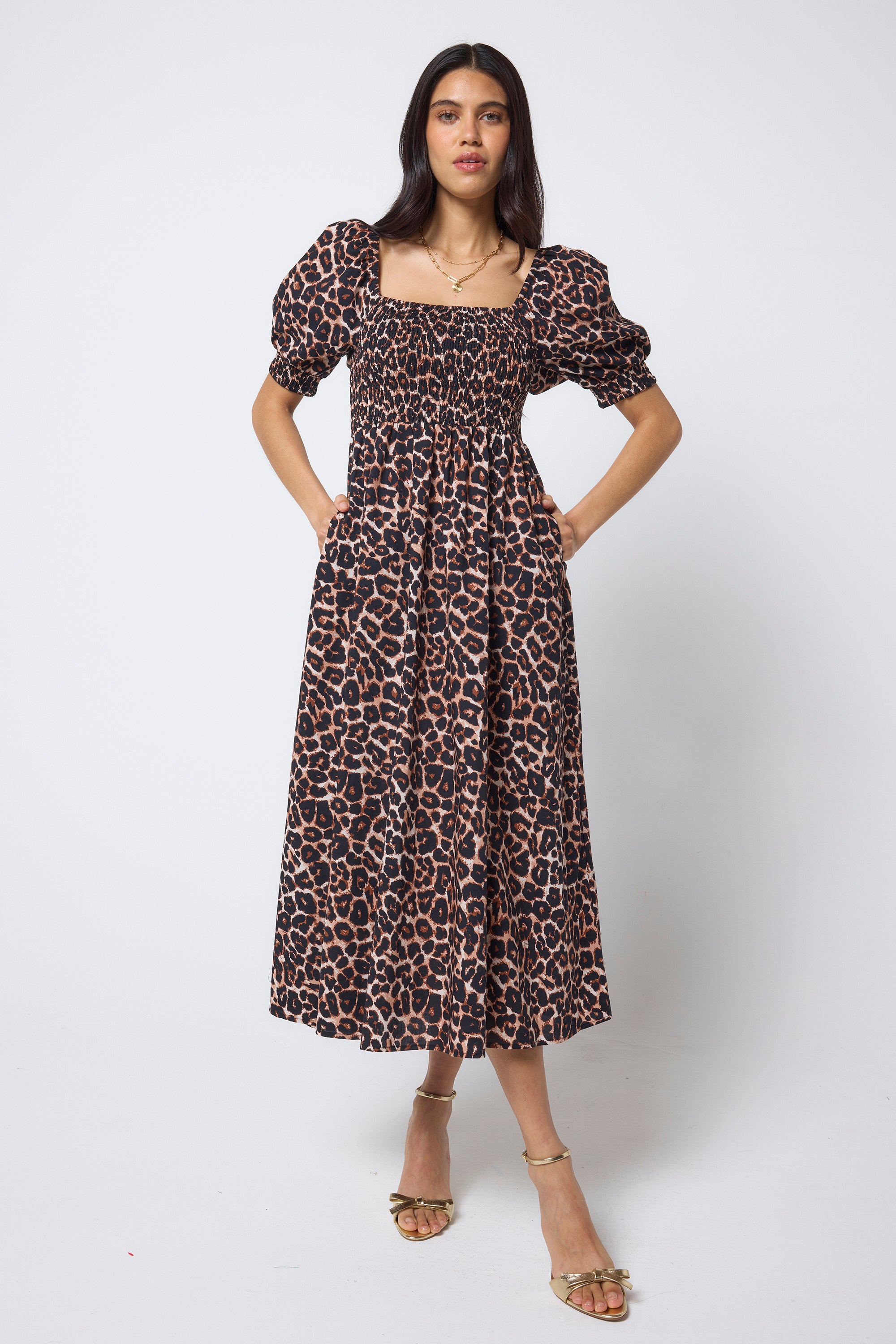Scamp & Dude Neutral Jaguar Shirred Square Neck Midi Dress | Model wearing a jaguar print dress with gold high heels.