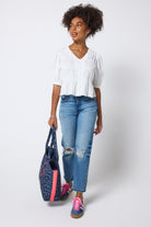 Scamp & Dude White Puff Sleeve Smocked Blouse | Model wears a short sleeve smocked blouse with distressed blue jeans and trainers.