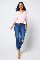 Scamp & Dude Pink Puff Sleeve Smocked Blouse | Model wears a smocked short sleeve blouse with a pair of distressed boyfriend jeans and heels.