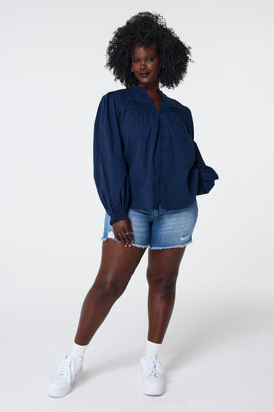 Scamp and Dude Navy Dobby Frill Neck Blouse | Model wearing long sleeve blouse featuring puff sleeves with frill neck and dobby detail.