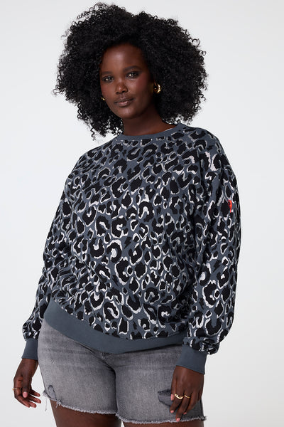 Scamp and Dude Grey with Black and Silver Foil Leopard Oversized Sweatshirt | Model wearing grey sweatshirt in an oversized fit with black and silver foil leopard print paired with denim shorts.