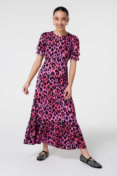 Scamp and Dude Pink and Lilac with Black Shadow Leopard Flute Sleeve Midi Dress | Model wearing a pink and lilac round neck midi dress in a black shadow leopard print. The dress features flute sleeves and has been paired with black pumps.