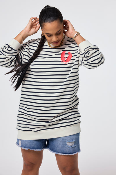 Scamp and Dude Ivory with Navy Stripe Placement Bolt Graphic Oversized Tunic | Model wearing round neck ivory tunic in an oversized fit featuring navy stripe and placement bolt graphic paired with denim shorts.