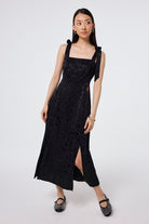 Scamp and Dude Black Jacquard Leopard Tie Shoulder Dress | Model wearing a black tie shoulder midi dress in a jacquard finish with two splits at the seam, paired with black pumps.