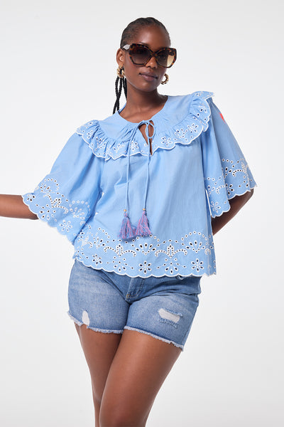 Scamp and Dude Blue Cutwork Blouse | Model wearing blue cutwork blouse featuring a tie front with tassel detail.
