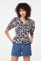 Scamp and Dude Ivory with Rainbow Shadow Leopard Button Through Blouse | Model wearing an ivory blouse with rainbow shadow leopard print featuring button detail, paired with scallop detail denim shorts.