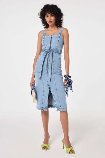 Scamp and Dude Pale Indigo Wash Scallop Strappy Denim Sundress | Model wearing a pale indigo wash denim sundress featuring scallop detail with a zip front closure and tie waist detail.