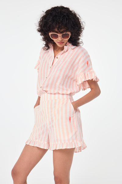 Scamp and Dude Coral and White Stripe Frill Hem Shorts | Model wearing coral and white stripe shorts with a matching shirt and a pair of sunglasses.