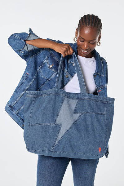 Scamp and Dude Authentic Indigo Patchwork Bolt Denim Tote Bag | Model wearing denim jeans and jacket paired with a white t-shirt holding a Authentic Indigo Patchwork Bolt Denim Tote Bag.