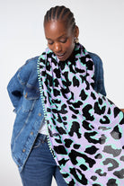 Scamp and Dude Lilac and Green with Black Mega Leopard Charity Super Scarf | Model wearing a denim jacket and jeans with our lilac and green with black mega leopard charity super scarf.