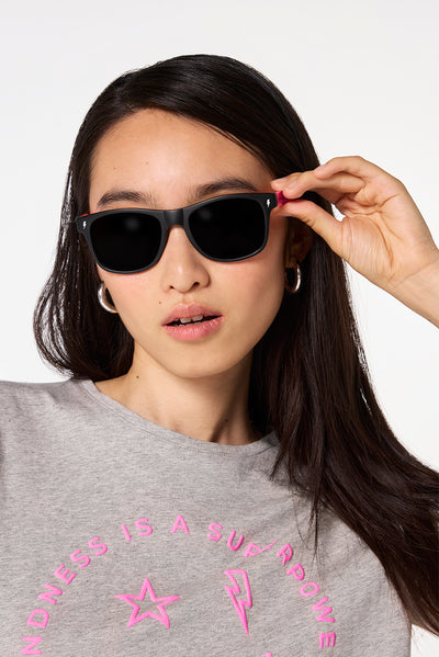Scamp and Dude 'Neon Sunnies' Black with Orange and Neon Pink | Model wearing black sunglasses with orange and neon pink detail.