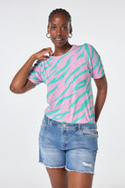 Scamp and Dude Pink with Green Graphic Tiger T-Shirt | Model wearing a pink crew neck t-shirt with green graphic tiger print, paired with distressed washed indigo denim shorts.