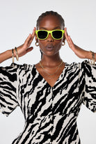 Scamp and Dude 'Neon Sunnies' Yellow | Model wearing neon yellow sunglasses with an ivory and black dress.