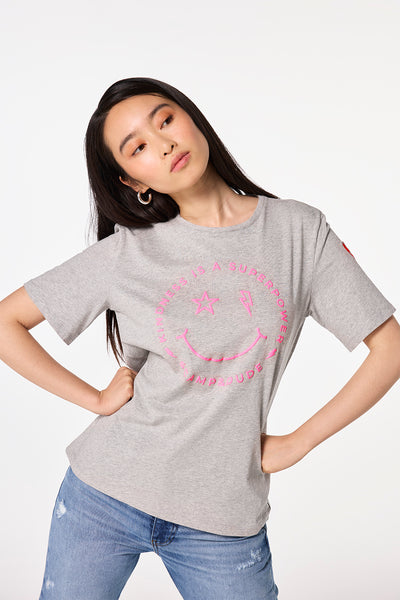 Scamp and Dude Grey Marl Smiley Face T-Shirt | Model wearing grey marl crew neck t-shirt featuring a pink smiley graphic print on the front.