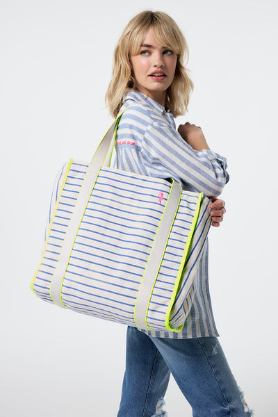 Scamp and Dude Blue and Ivory Stripe Zip Pocket Canvas Tote Bag | Model wearing jeans with a blue and white stripe oversized shirt with a canvas tote bag featuring a zip pocket.