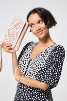 Scamp and Dude Taupe with Gold Lightning Bolt Laser Cut Clutch Bag | Model wearing a black and white cheetah print dress paired with a taupe clutch bag featuring laser cut lightning bolt detail.