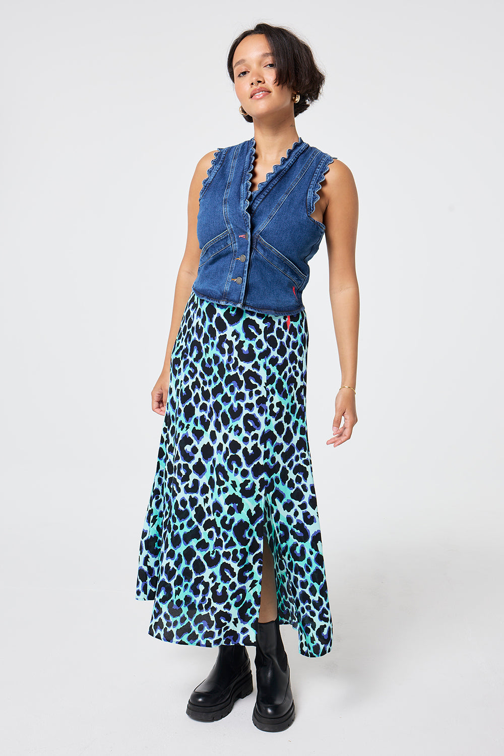 Scamp and Dude Turquoise with Black and Blue Shadow Leopard Split Front Skirt | Model wearing a scallop detail denim waistcoat paired with a turquoise midi skirt with black and blue leopard print.