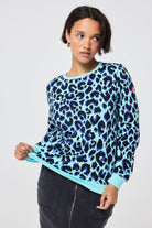 Scamp and Dude Turquoise with Black and Blue Shadow Leopard Classic Sweatshirt | Model wearing a turquoise with blue and black leopard print round neck sweatshirt in a classic fit paired with a black denim skirt with zip front detail.