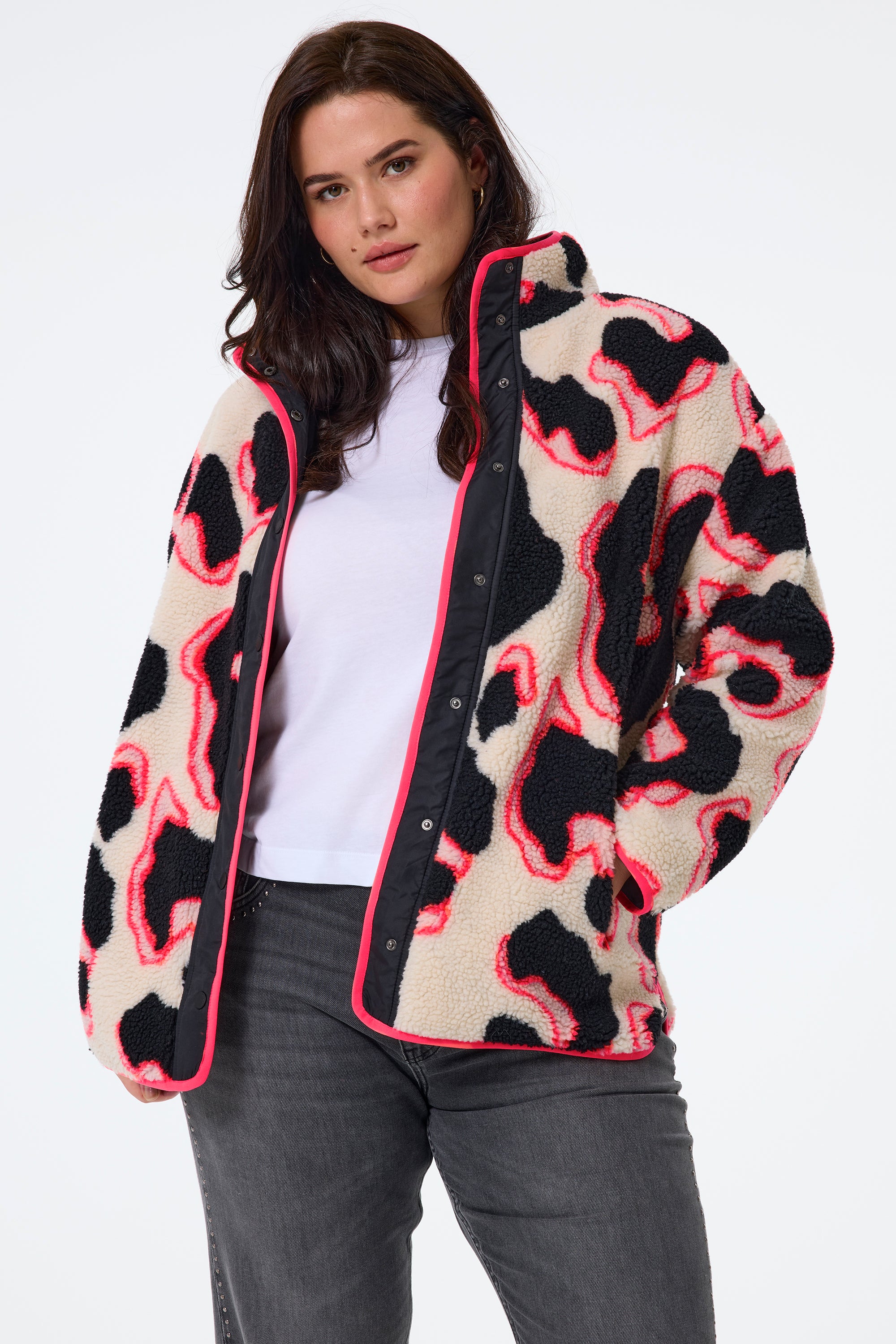 Scamp and Dude Cream with Coral and Black Mega Shadow Leopard Button Through Fleece Jacket | Model wearing washed black jeans with a white t shirt and a cream mega leopard print fleece featuring neon details.