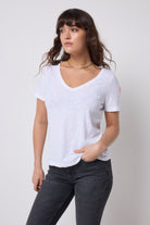 Scamp & Dude White V-Neck T-Shirt | Model wearing a white t-shirt and dark jeans with gold jewellery.