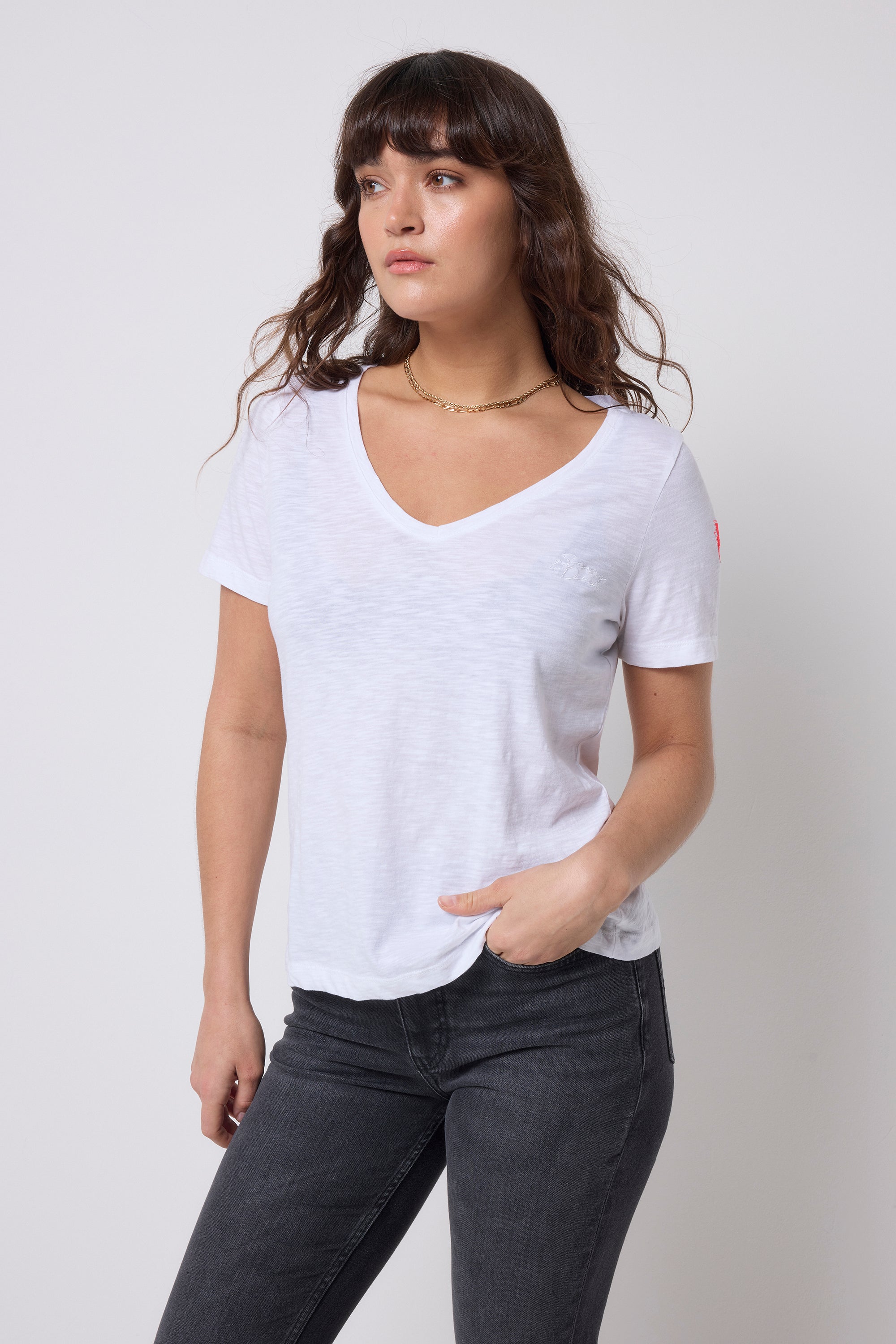 Scamp & Dude White V-Neck T-Shirt | Model wearing a white t-shirt and dark jeans with gold jewellery.