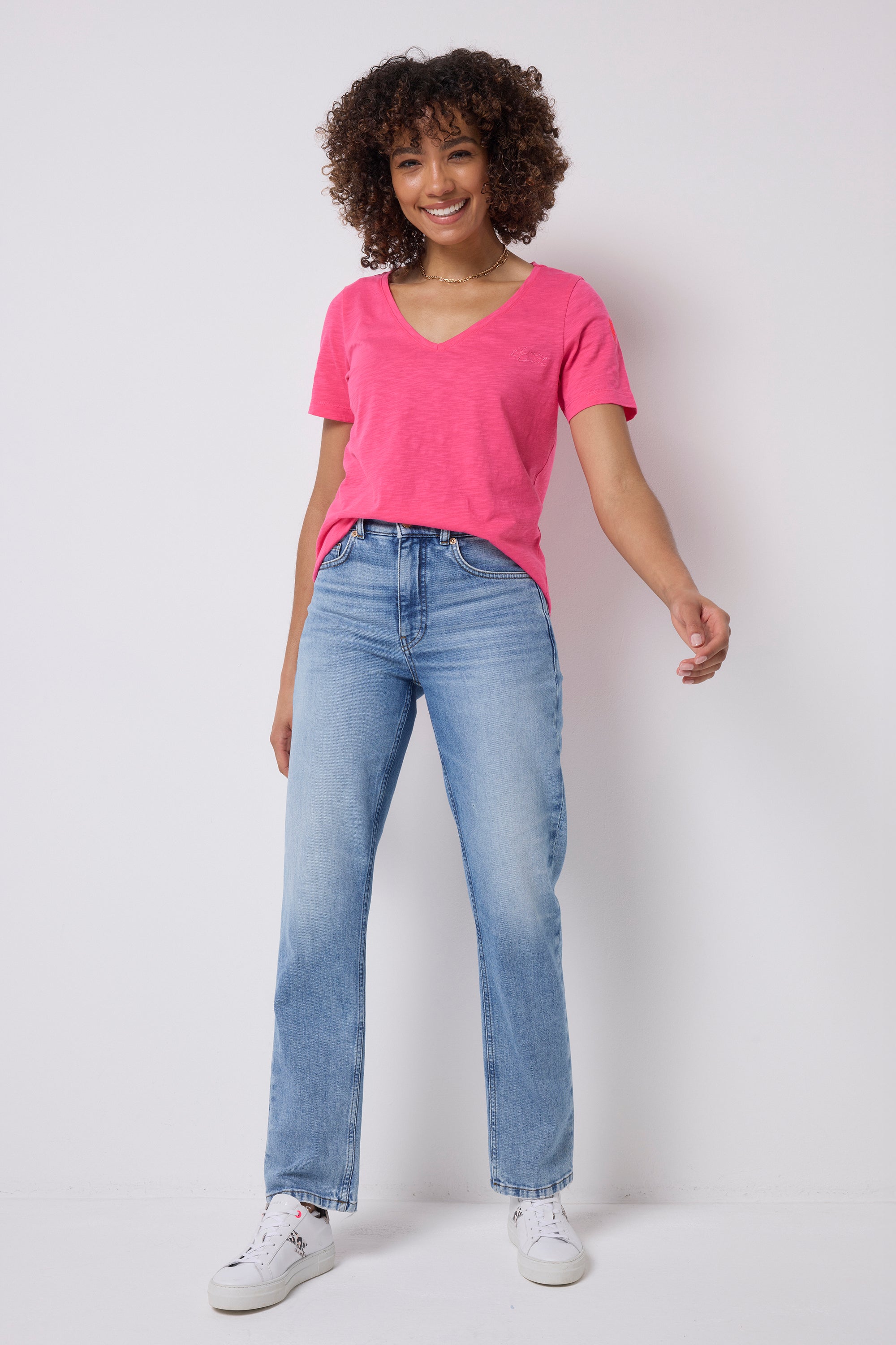 Scamp & Dude Pink V-Neck T-Shirt | Model wearing a pink v-neck t-shirt shirt with blue jeans and white trainers.