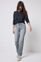 Scamp & Dude Grey Distressed Boyfriend Jeans | Model wearing a pair of grey distressed jeans with a navy jaguar print knitted jumper and trainers.
