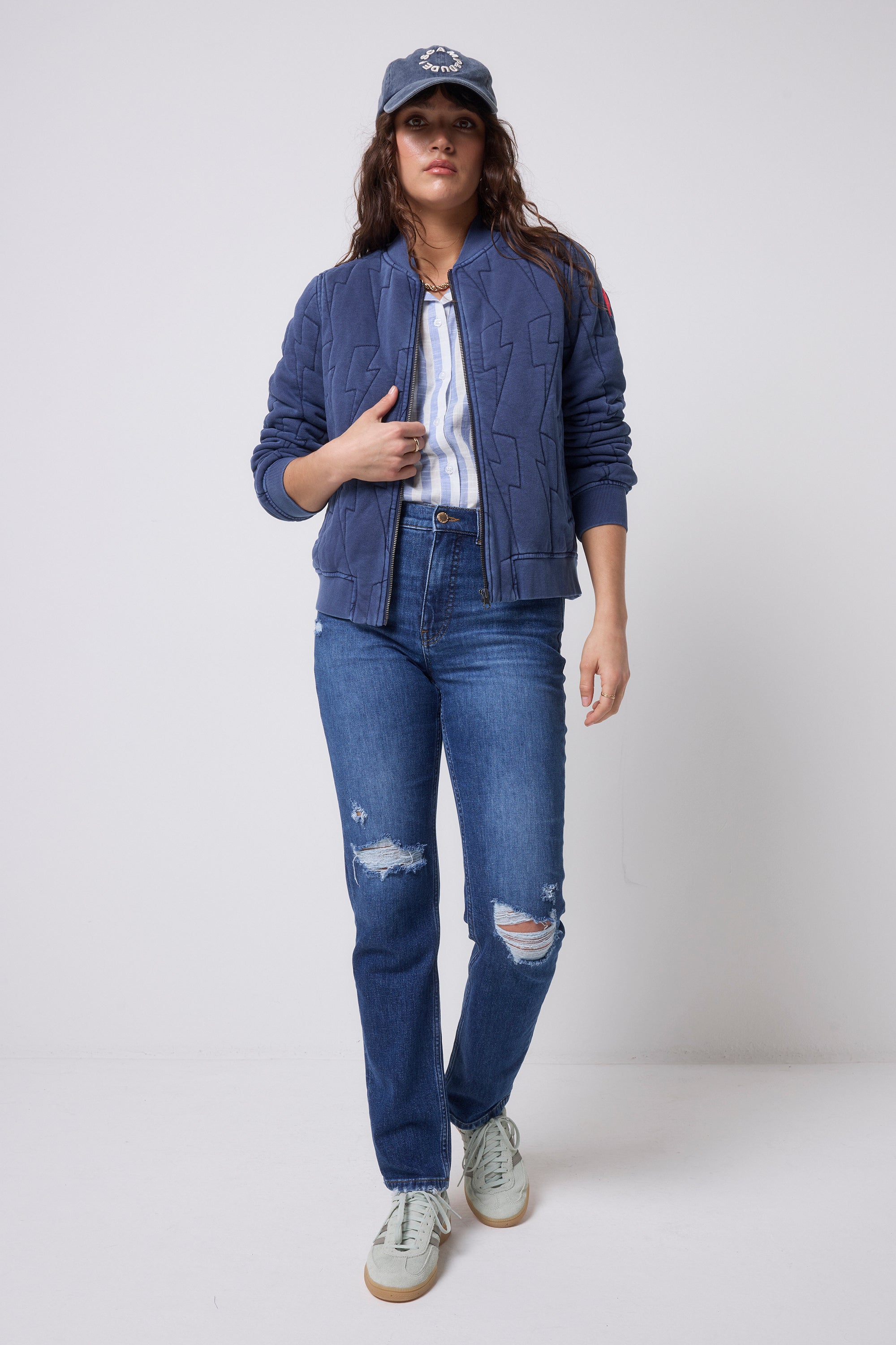 Scamp and Dude Navy Lightning Bolt Fitted Quilted Bomber Jacket | Model wearing a pair of blue distressed jeans, a stripe shirt and navy bomber jacket.