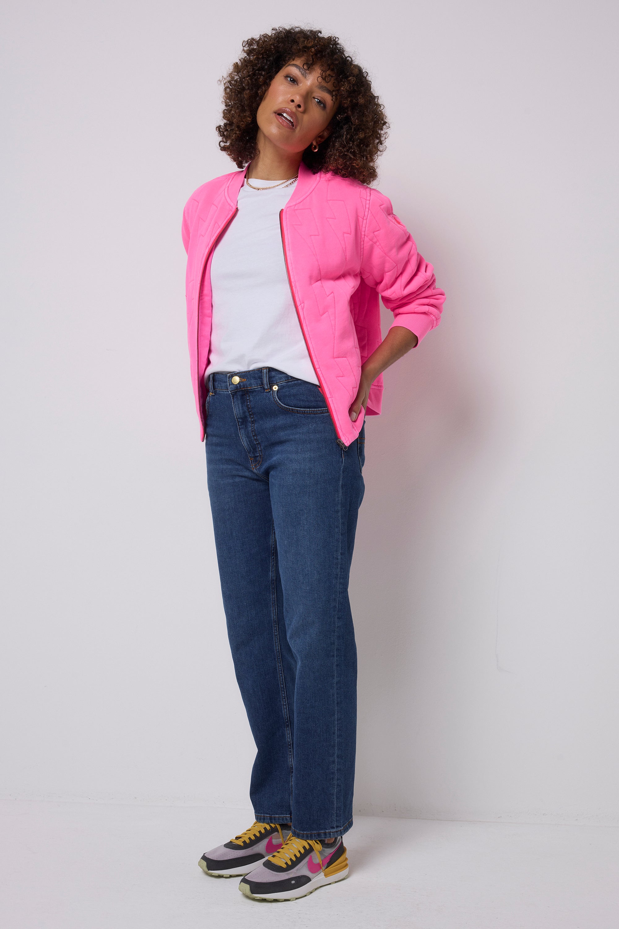 Scamp and Dude Neon Pink Lightning Bolt Fitted Quilted Bomber Jacket | Model wearing dark blue jeans with a white t-shirt and pink bomber jacket.