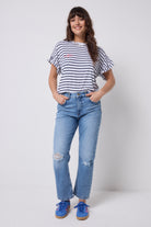 Scamp and Dude White with Navy Stripe Frill Sleeve T-Shirt | Model wearing a pair of distressed jeans with a round neck stripe t-shirt and frill sleeves.