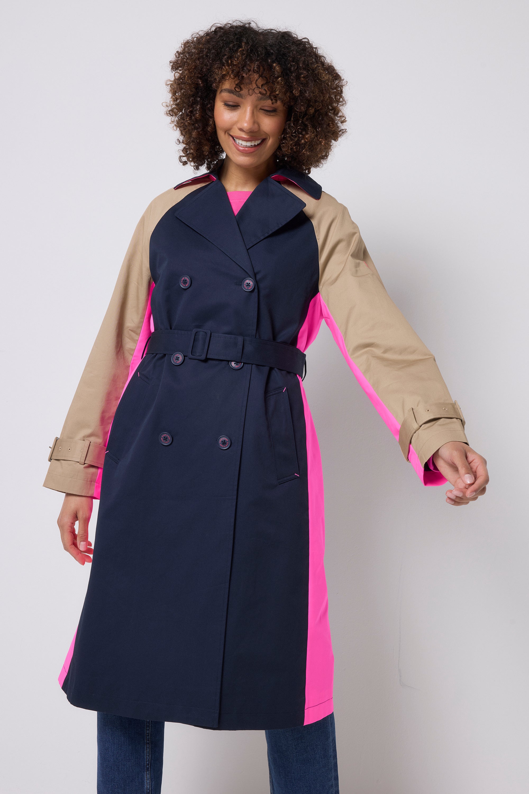 Scamp & Dude Navy and Stone Colourblock Trench Coat | Model is wearing a navy and stone colourblock trench coat with pink details. Worn with dark blue jeans.