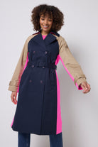 Scamp & Dude Navy and Stone Colourblock Trench Coat | Model is wearing a navy and stone colourblock trench coat with pink details. Worn with dark blue jeans.