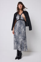 Scamp & Dude Grey Cheetah Lace Trim Puff Sleeve Midi Tea Dress | Model wearing a cheetah print dress with a black jacket and boots on a white background.