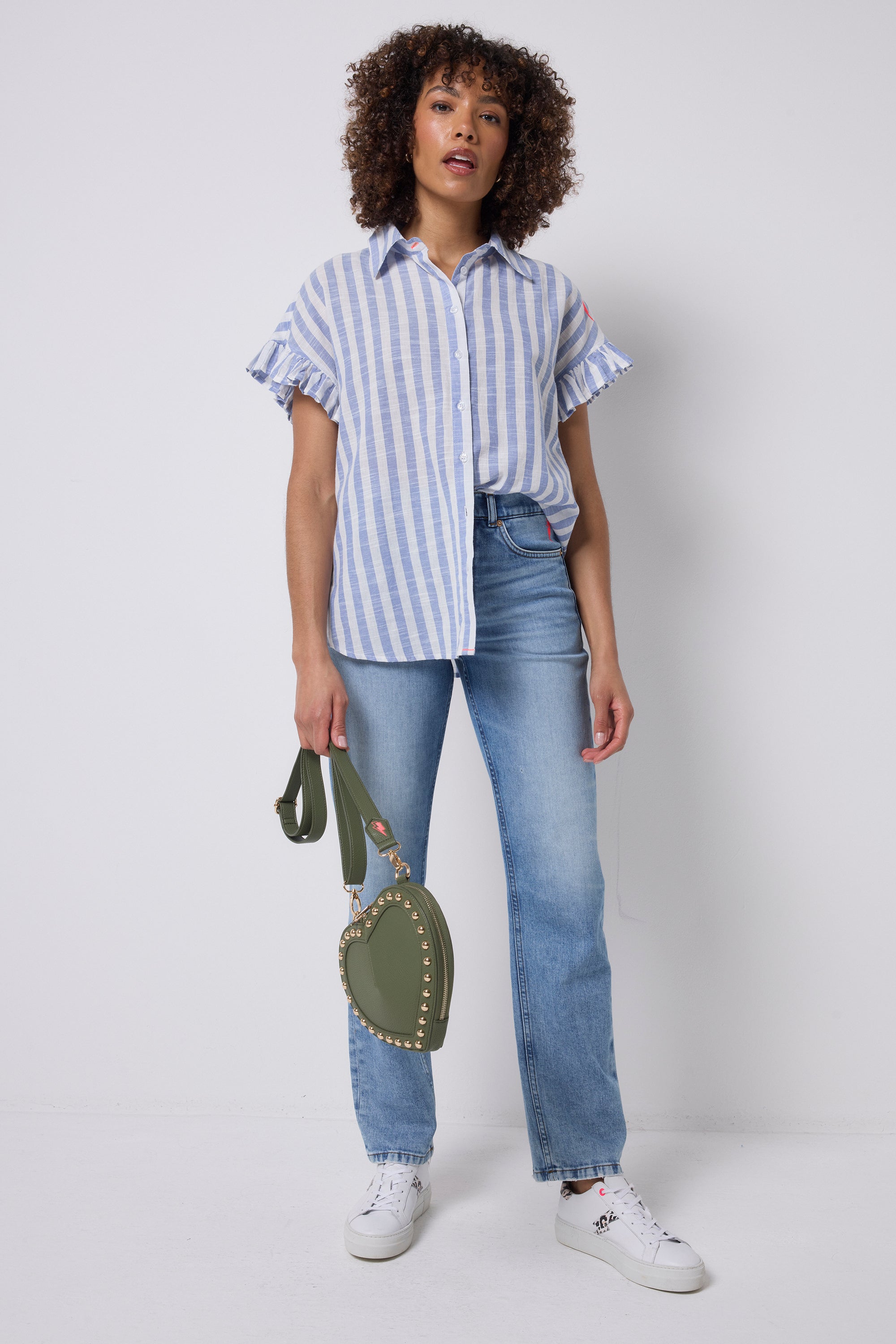Scamp & Dude Blue and White Stripe Frill Sleeve Shirt | Model wearing a blue and white stripe shirt featuring frill sleeves. Worn with blue boyfriend jeans and white trainers.