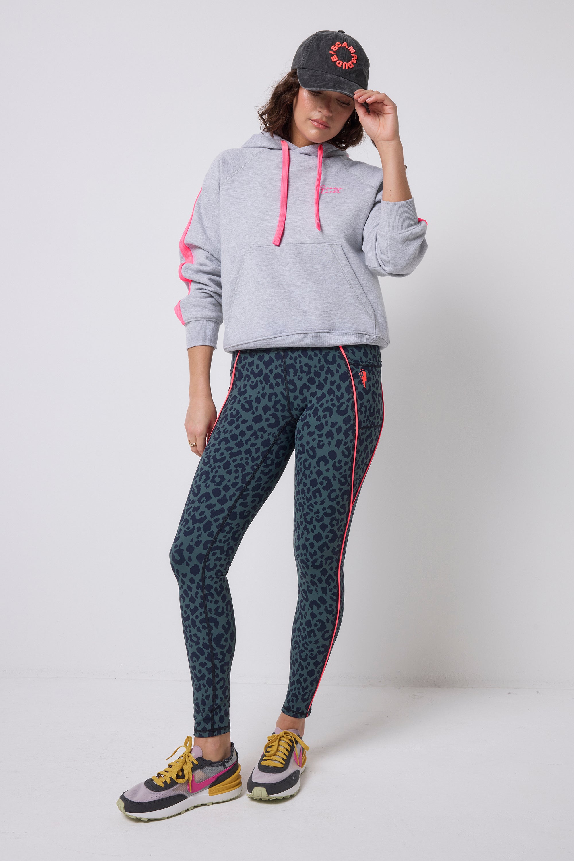 Scamp & Dude Khaki with Navy Candy Leopard Full Length Active Leggings | Model wearing a grey hoodie, khaki leopard print leggings, and colourful sneakers.