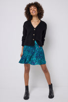 Scamp and Dude Turquoise with Blue Cheetah Skater Skirt | Model wearing a turquoise skater skirt with a black cardigan and black boots.