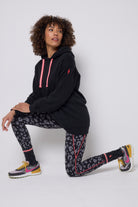 Scamp & Dude Black with Grey Leopard Full Length Active Leggings | Model wearing a pair of black activewear leggings with grey leopard print on them. Paired with a black longline hoodie, black socks and trainers.