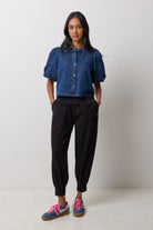 Scamp & Dude Black Barrel Joggers | Model wearing a denim button front puff sleeve top with black jogger pants and navy cheetah Gola trainers.
