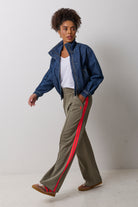 Scamp & Dude Khaki Side Stripe Wide Leg Jersey Trousers | Model wearing a khaki wide leg trousers with coral side stripe detail. Worn with a white v-neck t-shirt and a blue denim bomber jacket.