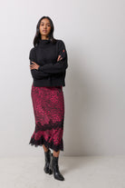 Scamp & Dude Black Cherry Cheetah Lace Insert Midi Skirt | Model wearing a black cherry lace trim skirt with a black roll neck knitted jumper and black heeled boots.