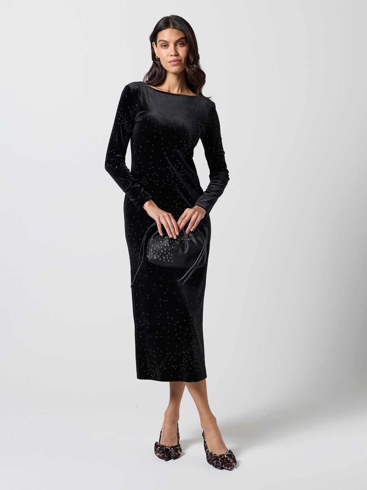 Scamp & Dude Black Velvet Stud Midi Dress | Model is wearing a long sleeve velvet dress with stud detail. Holding a black star studded bag and high heels.