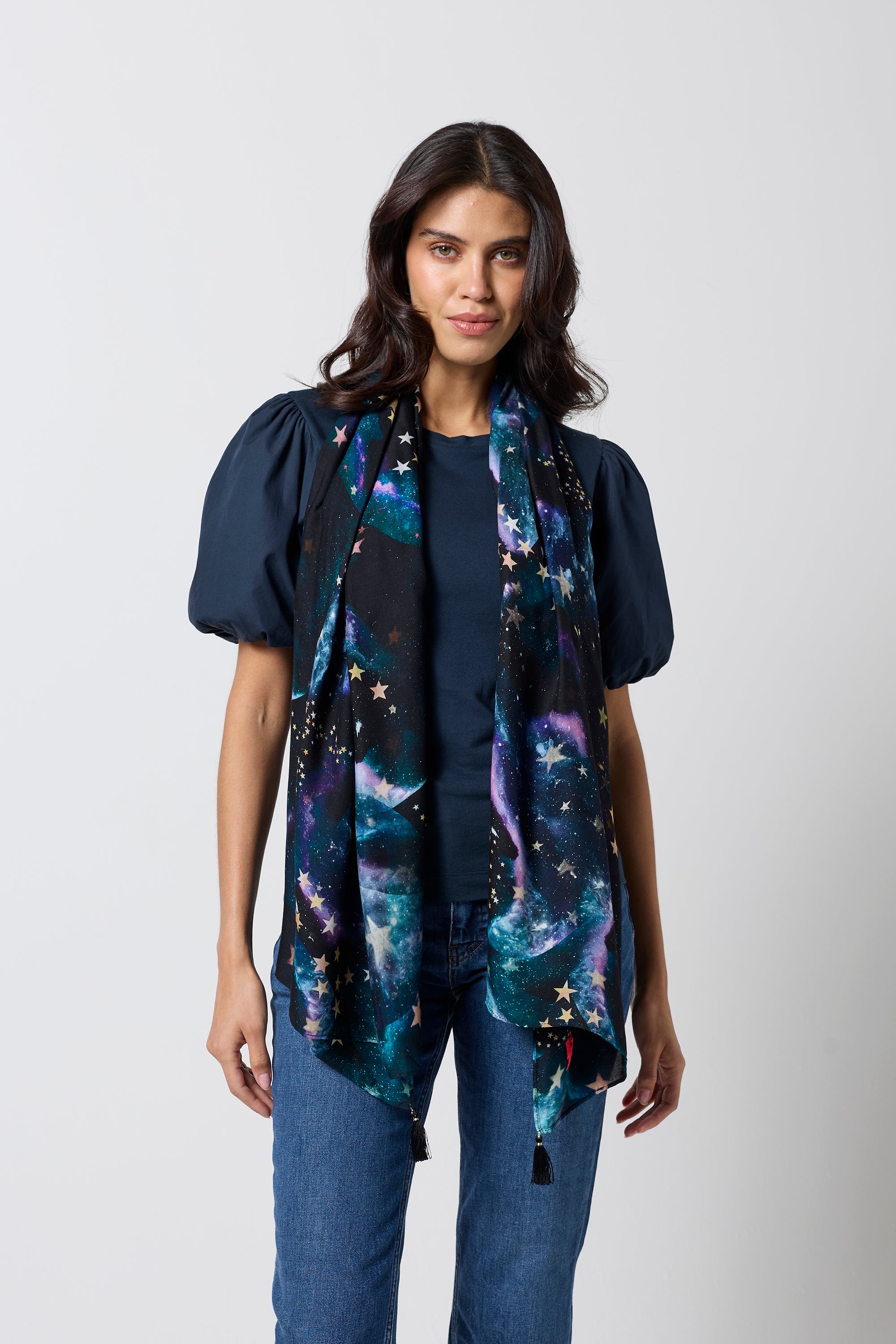 Scamp & Dude Black Galaxy with Stars Charity Super Scarf | Model wearing a navy puff sleeve t-shirt with a galaxy print super scarf and blue jeans.