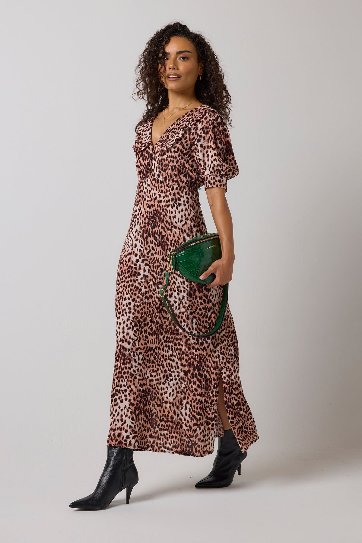 Scamp & Dude Neutral Cheetah Collared Midi Tea Dress | Model wearing a cheetah-print midi dress with puff sleeves and a side slit, holding a green handbag and wearing black pointed-toe heeled boots.