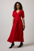 Scamp & Dude Red with Black Cheetah Spot Drop Waist Midi Dress | Model wearing a red animal print midi  with a pair of black boots.