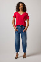 Scamp & Dude Red V-Neck T-Shirt | Model wearing a red v-neck t-shirt with a pair of barrel leg jeans and high heels.
