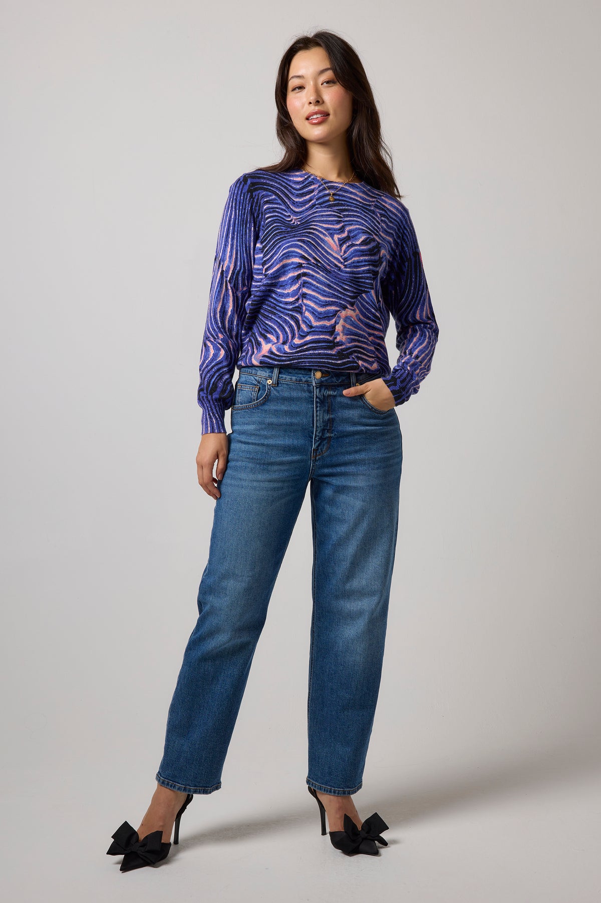 Scamp & Dude Blue Tiger Moth Printed Knit Jumper | Model wearing a long-sleeve blue and purple tiger moth knitted top with a pair of blue jeans.