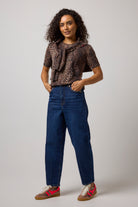 Scamp & Dude Neutral Milano Leopard Short Sleeve Printed Knit Jumper | Model wearing a pair of blue jeans with a leopard print knit top and cheetah print trainers.